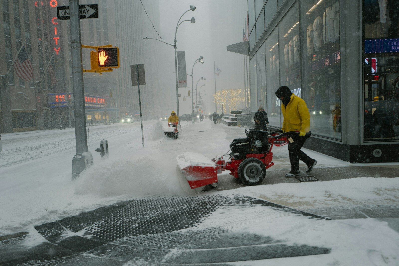 Man clearing snow with a snowblower on a city street.